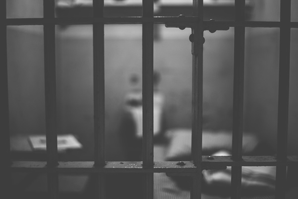 A blurred black and white image of a prisoner behind bars