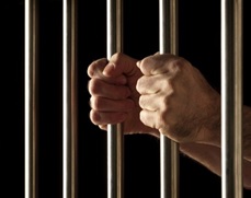 A convict holding jail bars