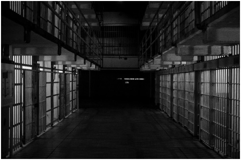 Dark prison corridor with cells