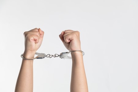 Person holding up handcuffed hands.