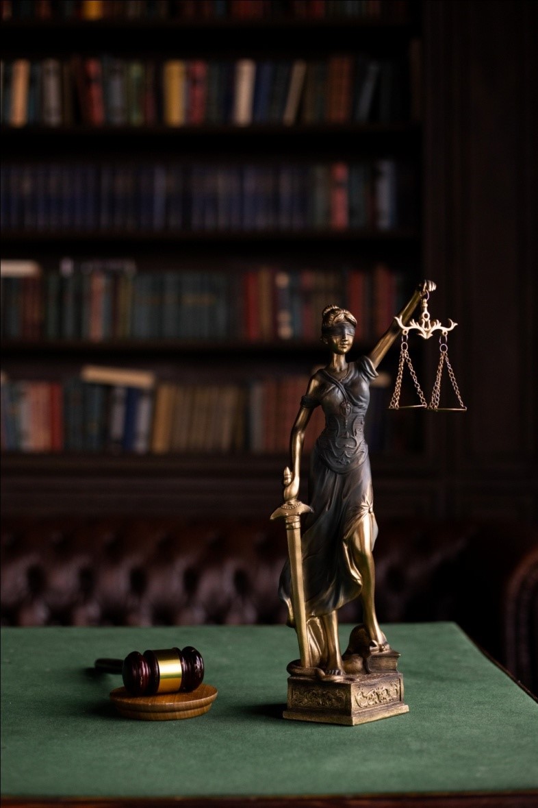 Lady justice and a gavel on a green table.