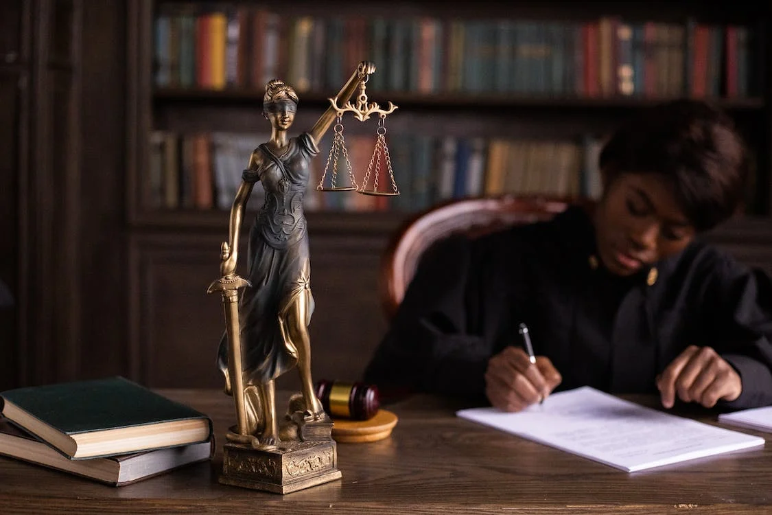 An image of a lady justice writing on papers