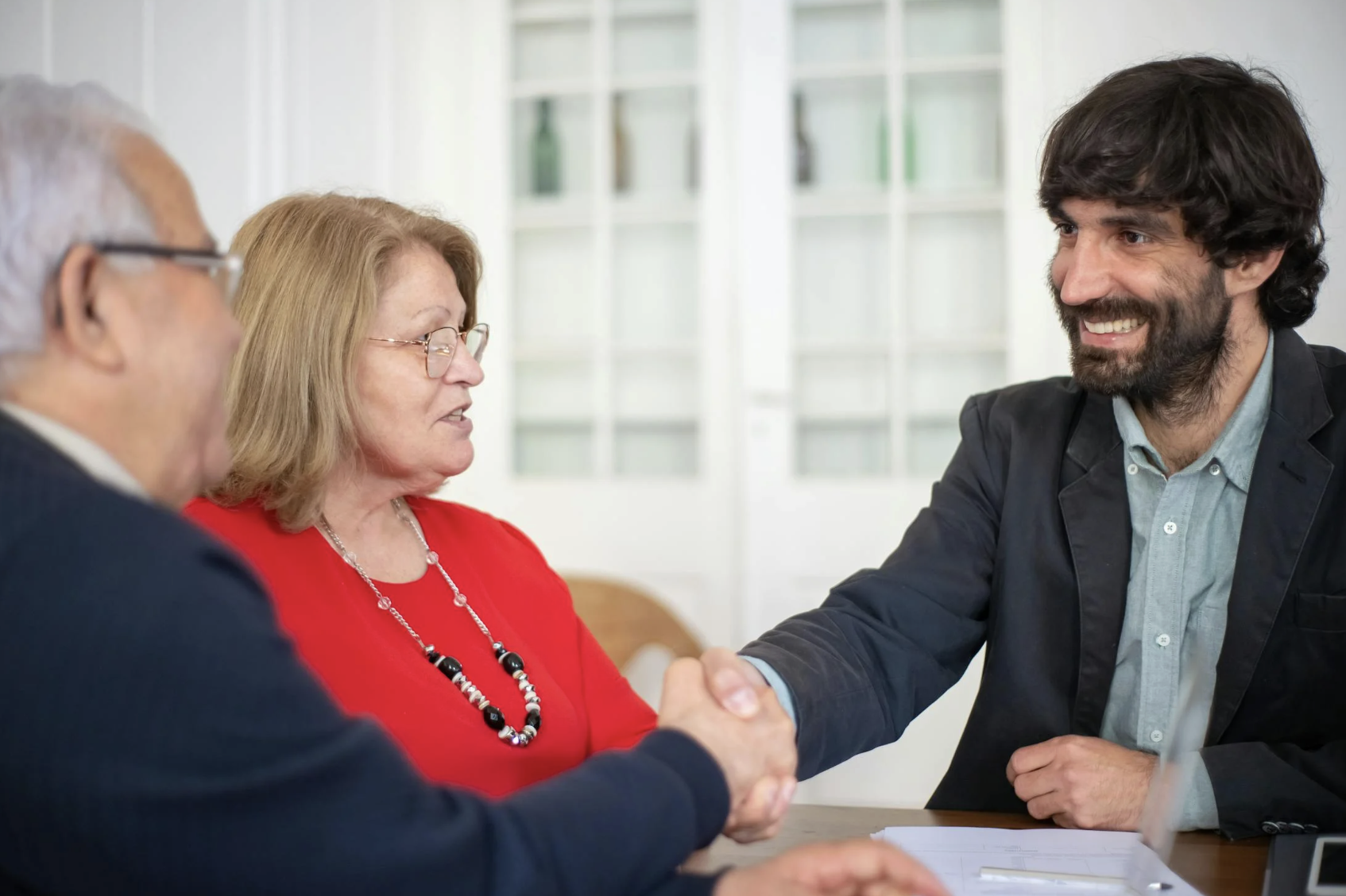  This photo shows an elderly couple shaking hands with a legal adviser over a desk.
