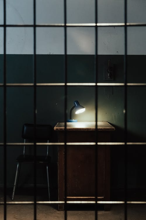 a desk and a lamp inside a jail cell