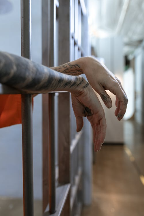 a person's hands sticking out of a jail cell