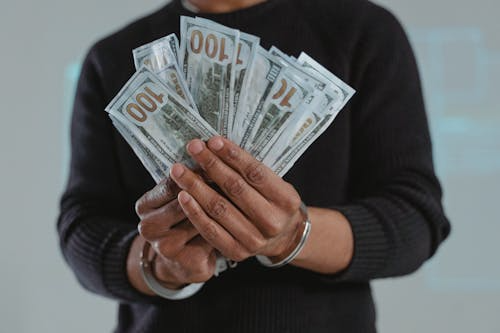 A person in handcuffs holding dollars