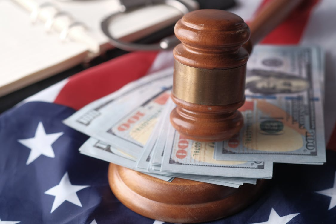 This photo shows a gavel on top of money.