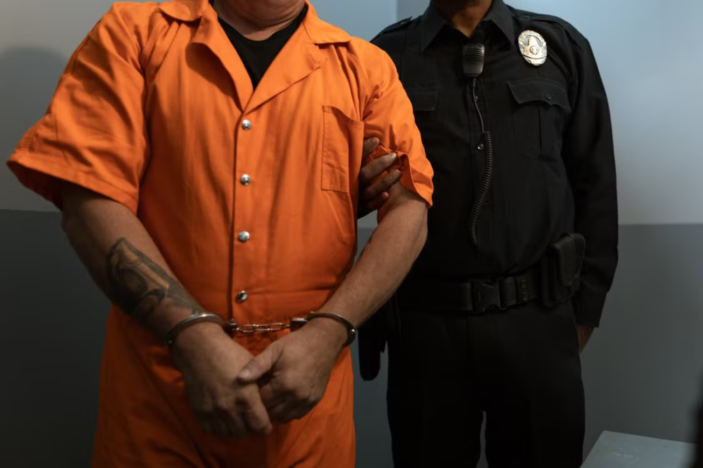 This photo shows an officer holding a prisoner’s arm.