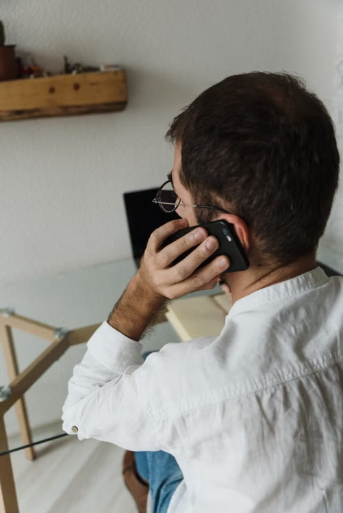 Person sitting at a desk using a smartphone while handling bail-related information
