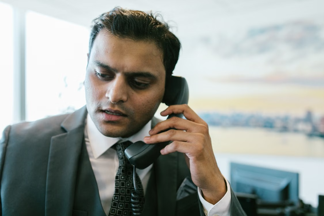 Man in a black suit holding a telephone while discussing bail bond assistance