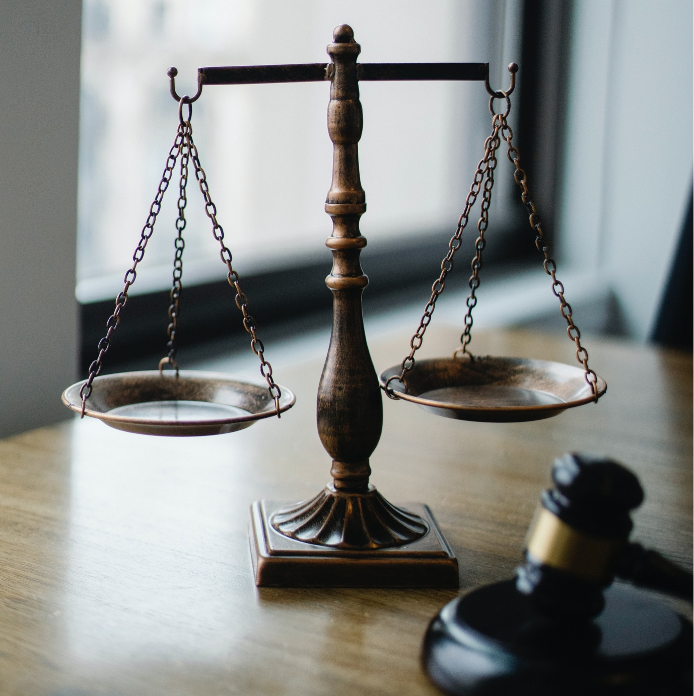 A legal scale and a judge's gavel on a wooden table